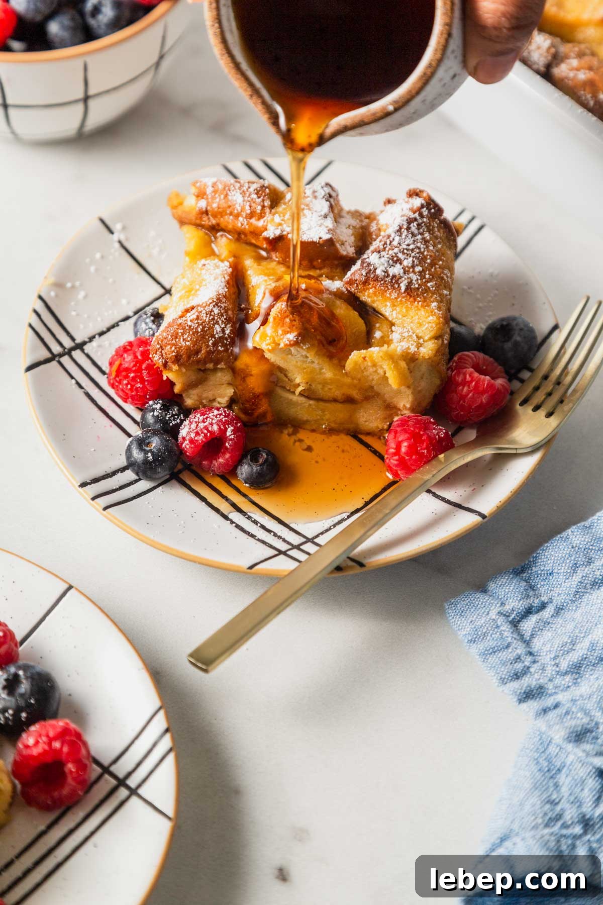Brioche French Toast Casserole Recipe for Brunch or Holidays 2 baked french toast casserole with maple syrup and berries.
