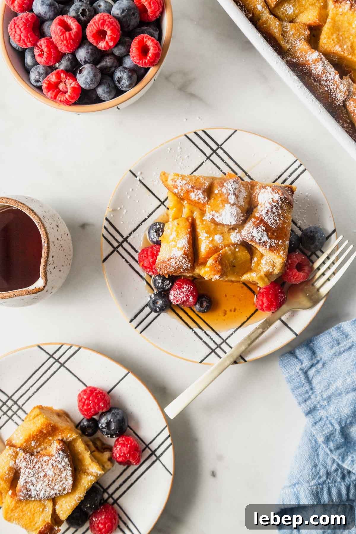Brioche French Toast Casserole Recipe for Brunch or Holidays 12 french toast casserole on a plate with berries and maple syrup.