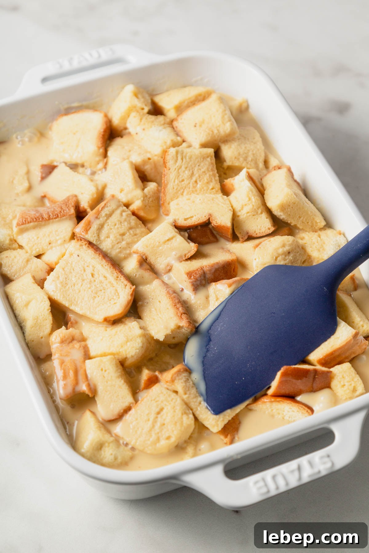 Brioche French Toast Casserole Recipe for Brunch or Holidays 9 patting the brioche bread down to soak the custard.