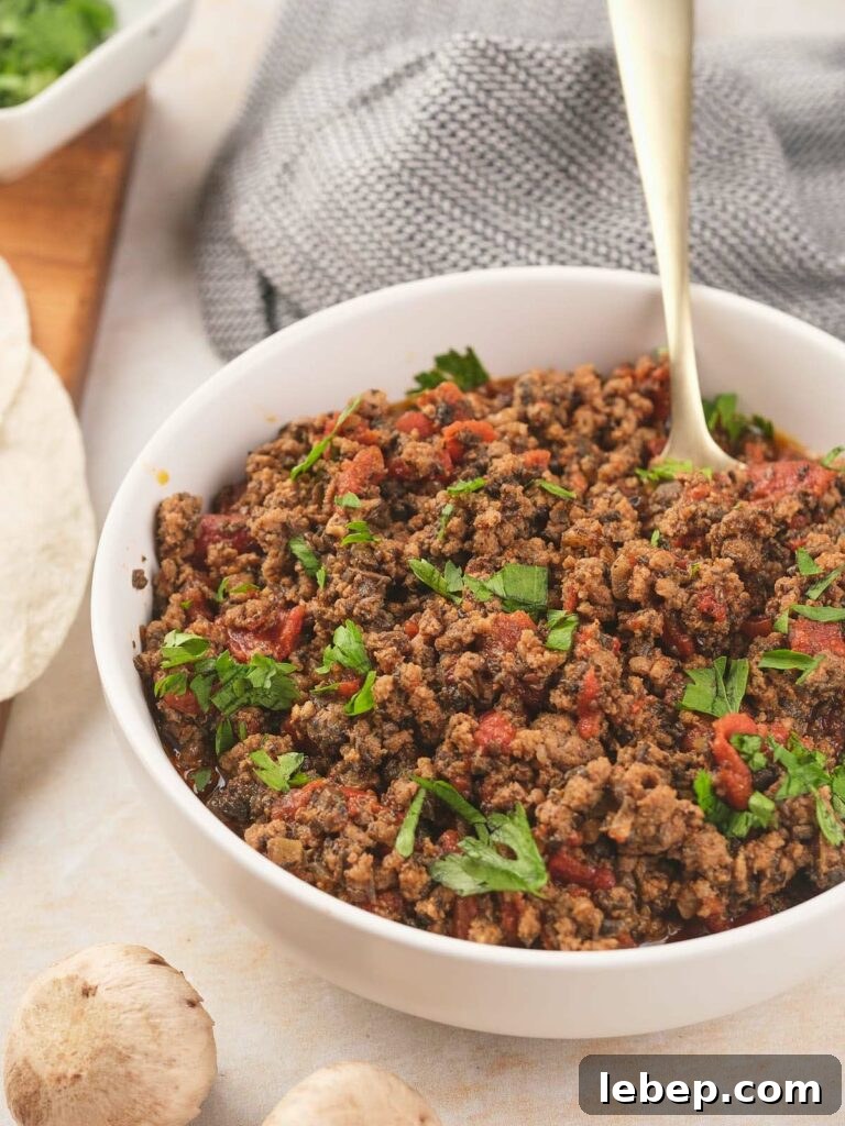 Mexican ground beef in a bowl with tortillas and mushrooms.