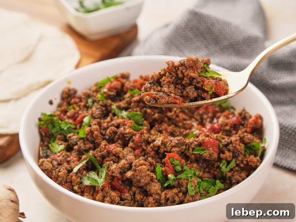 Mexican ground beef in a bowl with tortillas and mushrooms.