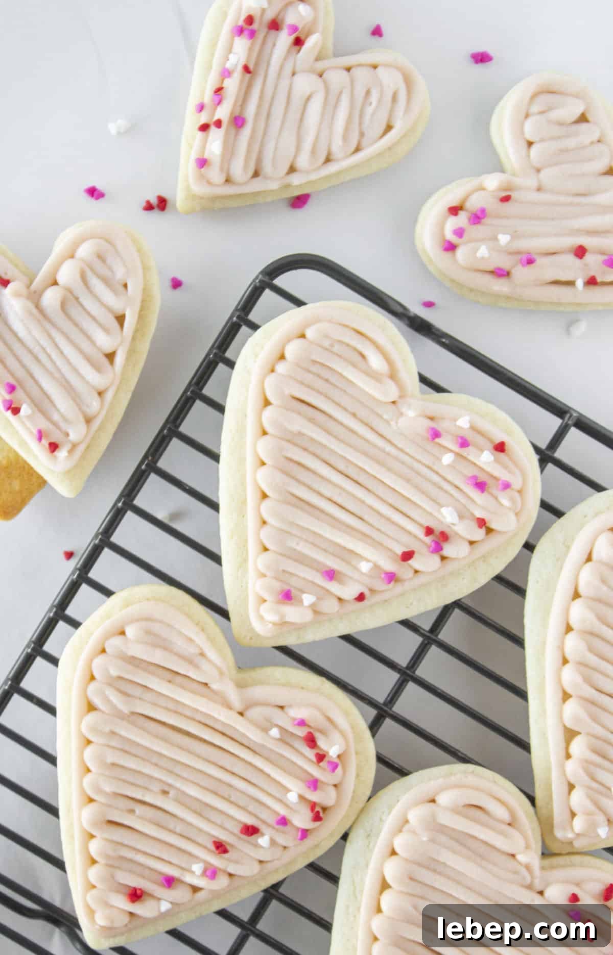 Heart Sugar Cookies with strawberry buttercream on a cooling rack.