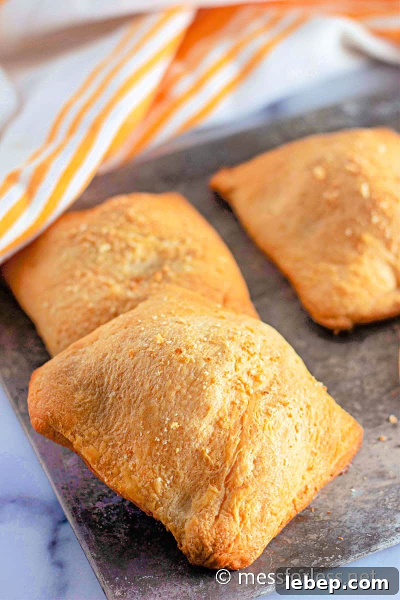 Cheesy Chicken Crescent Bake with Puff Pastry Squares 3 three Chicken Crescent Squares on cutting board with white and orange striped towel in background