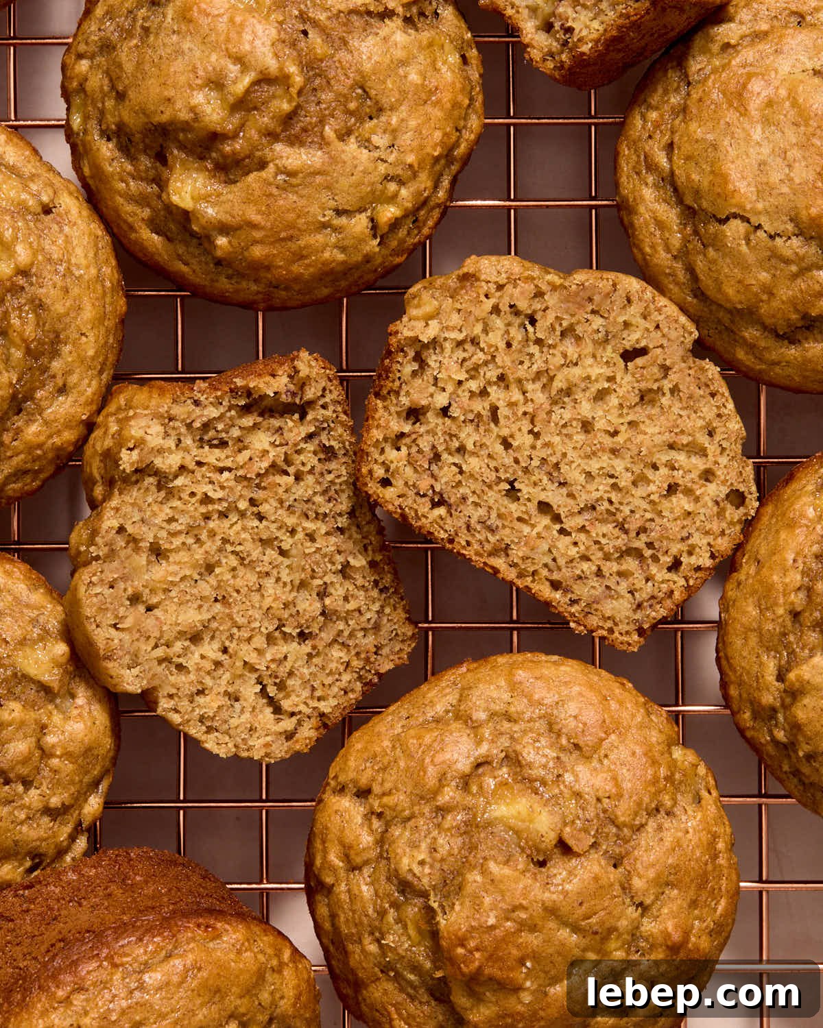 Spelt Flour Peanut Butter Banana Muffins — Naturally Sweetened 11 Muffins arranged on a wire rack with one cut in half to show the texture.
