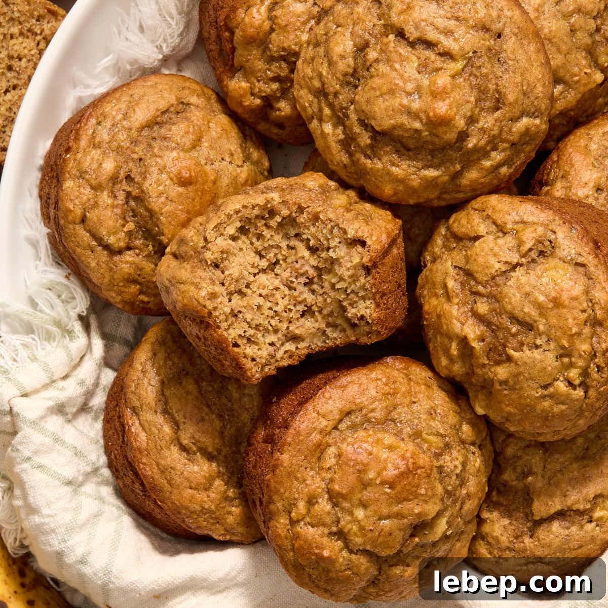 Overhead view of spelt flour peanut butter banana muffins in a napkin lined basket with a bite removed from one.
