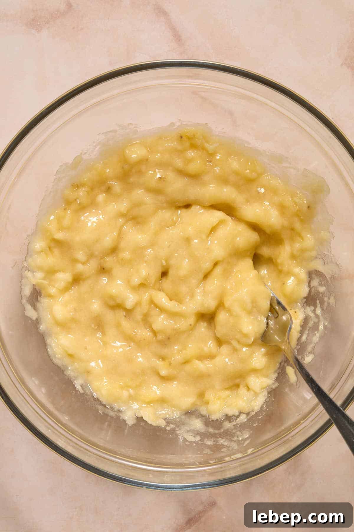 Spelt Flour Peanut Butter Banana Muffins — Naturally Sweetened 5 Bananas mashed together in a glass bowl with a fork.