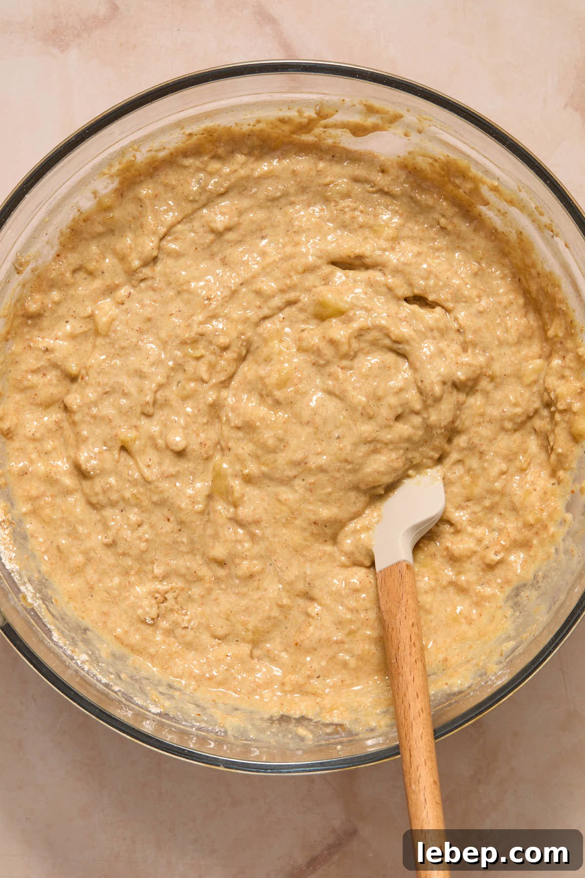 Spelt Flour Peanut Butter Banana Muffins — Naturally Sweetened 7 Banana muffin batter in a large glass bowl with a spatula inserted into it.