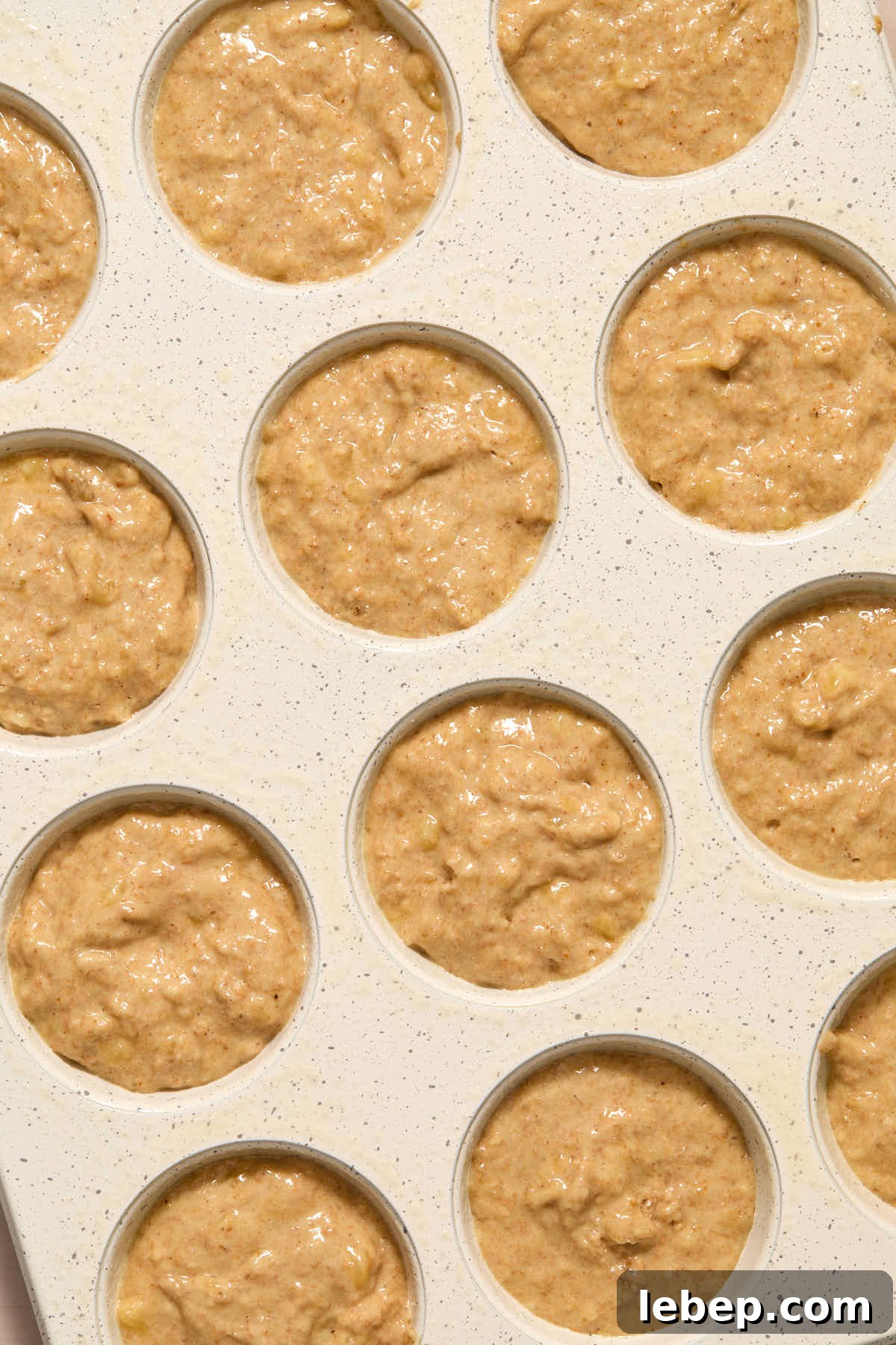 Spelt Flour Peanut Butter Banana Muffins — Naturally Sweetened 8 Muffin batter divided in a white muffin pan.