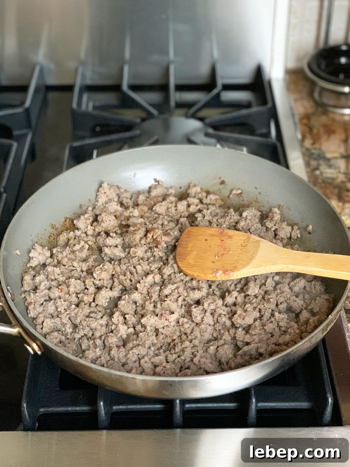 Sage Sausage Stuffing Recipe for Thanksgiving and Holiday Dinners 7 Saute pan with sausage cooked and a wooden spoon showing.
